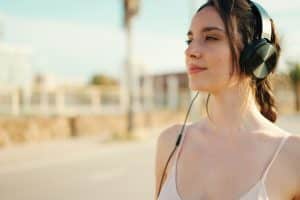 Young athletic woman with headphones relaxing and resting on the sea background