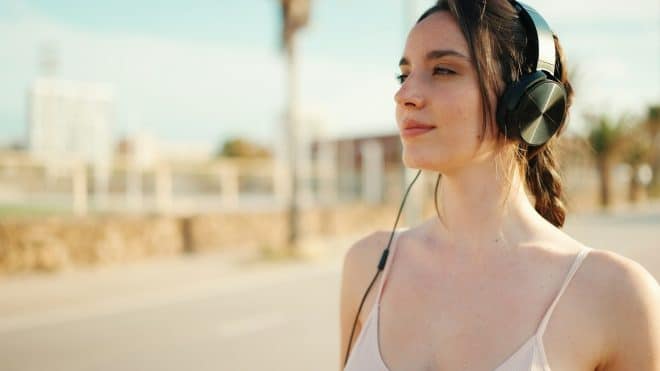 Young athletic woman with headphones relaxing and resting on the sea background